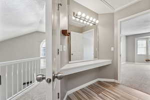 Bathroom featuring lofted ceiling, baseboards, a textured ceiling, and wood finished floors