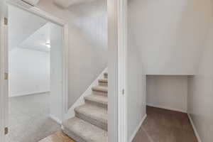 Staircase with vaulted ceiling, carpet flooring, and baseboards