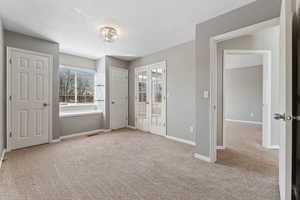 Unfurnished bedroom featuring baseboards, a textured ceiling, and light colored carpet