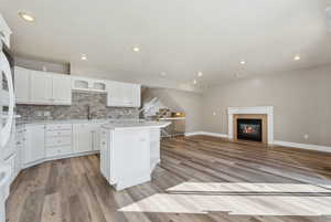 Kitchen featuring a center island, light wood finished floors, light countertops, glass insert cabinets, and white cabinets