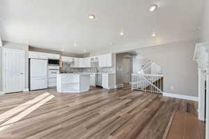 Kitchen with tasteful backsplash, appliances with stainless steel finishes, light countertops, light wood-style floors, and white cabinetry