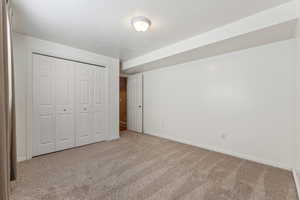 Unfurnished bedroom featuring baseboards, a closet, a textured ceiling, and light colored carpet