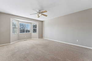 Carpeted empty room with ceiling fan and baseboards