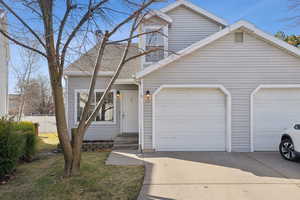 View of front of home with a garage, fence, concrete driveway, and entry steps