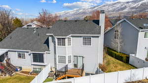 Back of property featuring roof with shingles, a chimney, a fenced backyard, and a mountain view