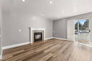 Unfurnished living room with light wood finished floors, recessed lighting, baseboards, and a tile fireplace