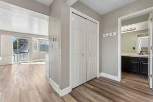 Hallway with light wood-style flooring, visible vents, baseboards, and a sink