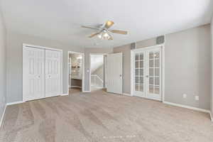 Unfurnished bedroom with baseboards, connected bathroom, ceiling fan, carpet, and french doors