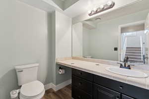 Bathroom featuring visible vents, baseboards, toilet, wood finished floors, and vanity