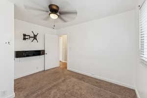 Carpeted empty room featuring baseboards and a ceiling fan