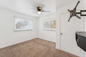 Unfurnished bedroom with light colored carpet and ceiling fan