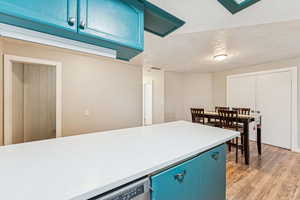 Kitchen with blue cabinets, light countertops, light wood-style floors, and dishwasher