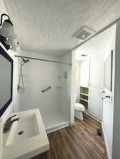 Bathroom featuring visible vents, a sink, a textured ceiling, and wood finished floors