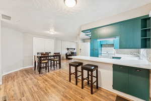 Kitchen with open shelves, white appliances, backsplash, a peninsula, and a kitchen bar