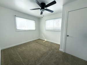 Spare room featuring baseboards, visible vents, dark carpet, and ceiling fan