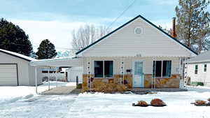 View of front of property with a carport, stone siding, and an outdoor structure