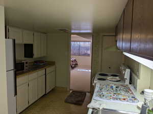 Kitchen with visible vents, white appliances, and white cabinetry