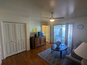 Living room featuring ceiling fan and dark wood-style flooring