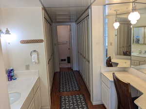 Bathroom with a closet, visible vents, vanity, and wood finished floors