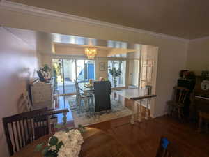 Dining room with crown molding, wood finished floors, and an inviting chandelier