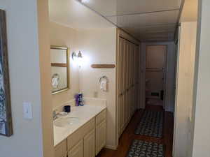 Bathroom with a closet, visible vents, vanity, and wood finished floors