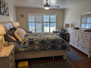 Bedroom with ceiling fan, multiple windows, and dark wood finished floors