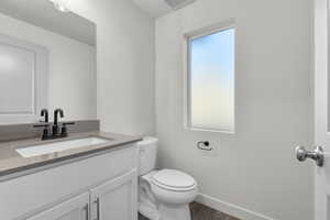 Bathroom with visible vents, baseboards, toilet, wood finished floors, and vanity