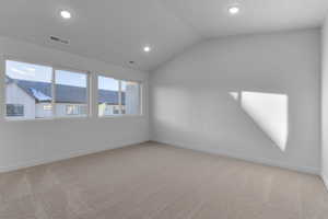 Unfurnished room featuring vaulted ceiling, carpet, and visible vents