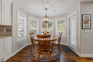 Dining room with a wealth of natural light, dark wood-style flooring, and visible vents