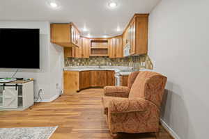 Kitchen featuring recessed lighting, white appliances, baseboards, light wood finished floors, and tasteful backsplash