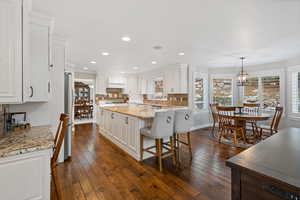 Kitchen featuring light stone countertops, white cabinetry, and pendant lighting