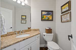 Bathroom featuring baseboards, visible vents, toilet, wood finished floors, and vanity