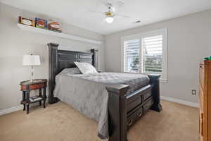 Bedroom with light carpet, a ceiling fan, visible vents, and baseboards