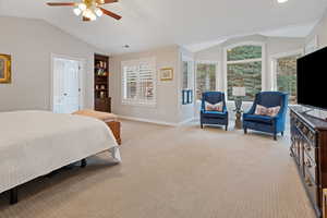 Bedroom with light carpet, baseboards, a ceiling fan, ensuite bath, and vaulted ceiling