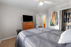 Carpeted bedroom with a closet, visible vents, ceiling fan, and baseboards