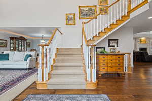 Stairs featuring a fireplace, crown molding, and wood finished floors