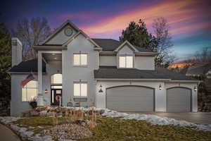 View of front of home with an attached garage, brick siding, driveway, roof with shingles, and a chimney