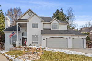 View of front of property featuring a garage, a shingled roof, brick siding, driveway, and a chimney