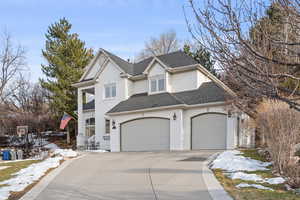 Traditional home featuring an attached garage, concrete driveway, brick siding, and a shingled roof