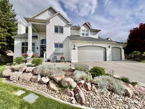 View of front of house with concrete driveway, brick siding, a garage, and a chimney
