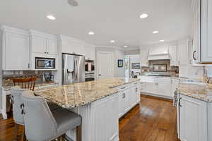 Kitchen with a kitchen island, appliances with stainless steel finishes, white cabinets, and a sink