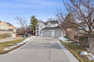 View of front facade featuring a residential view, driveway, an attached garage, and stucco siding