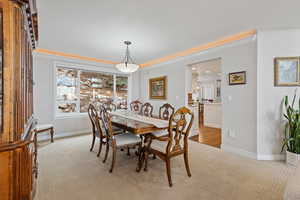 Dining area featuring ornamental molding, light colored carpet, and baseboards