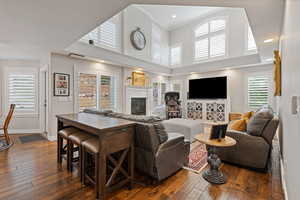 Living room with a high ceiling, baseboards, dark wood-style floors, a glass covered fireplace, and crown molding