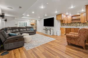 Living area with light wood finished floors, baseboards, visible vents, a fireplace, and recessed lighting