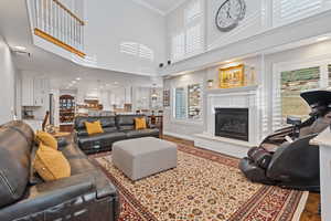 Living room featuring ornamental molding, a glass covered fireplace, baseboards, and wood finished floors