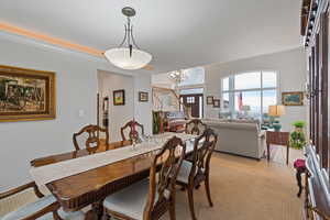 Dining space with stairs, a notable chandelier, and light colored carpet