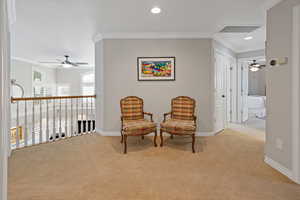 Living area featuring light carpet, ornamental molding, and baseboards