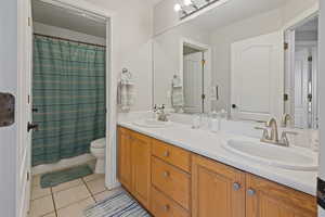 Full bathroom featuring double vanity, a sink, toilet, and tile patterned floors