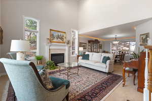 Living room with ornamental molding, a glass covered fireplace, light carpet, and a high ceiling